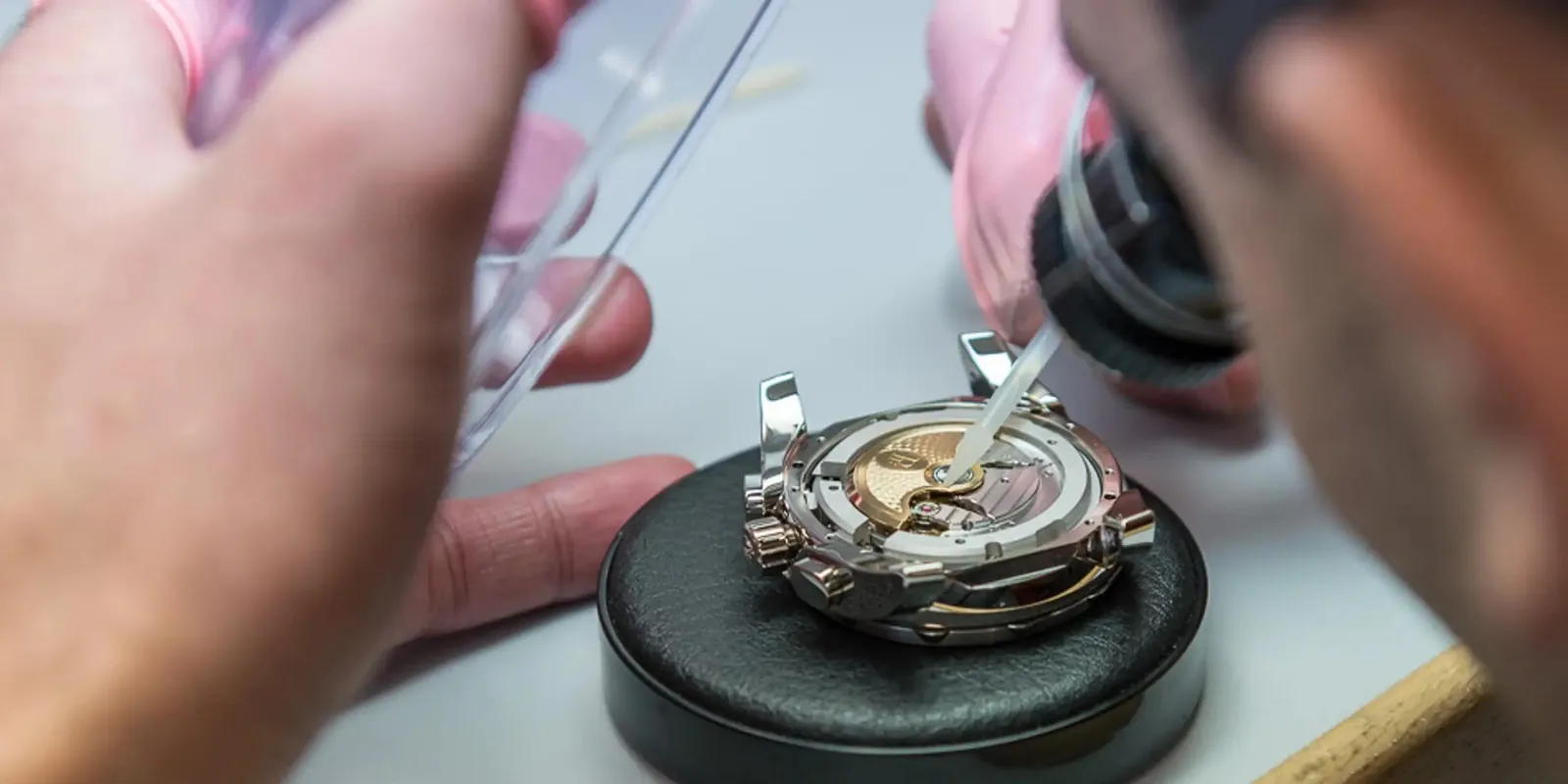 Watchmaker inspecting a watch movement during assembly, illustrating the preparation, prototyping, and quality control steps before production.